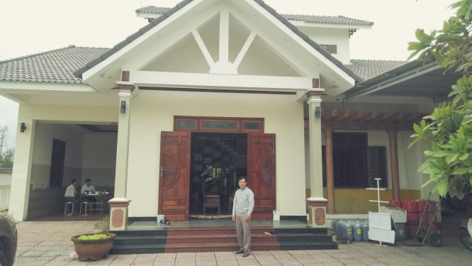 Anh Nguyễn Xuân Cần bên căn nhà xây dựng khang trang của mình